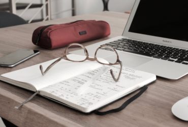 Documents and a laptop on a desk, illustrating equity research on artificial intelligence.